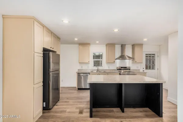 a kitchen with stainless steel appliances kitchen island granite countertop a refrigerator and a sink