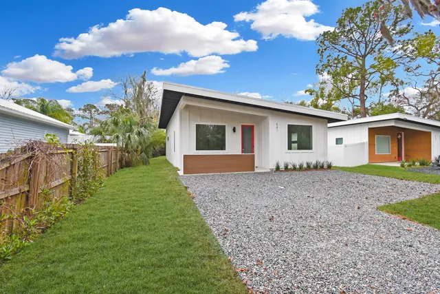 a view of house with backyard and bushes