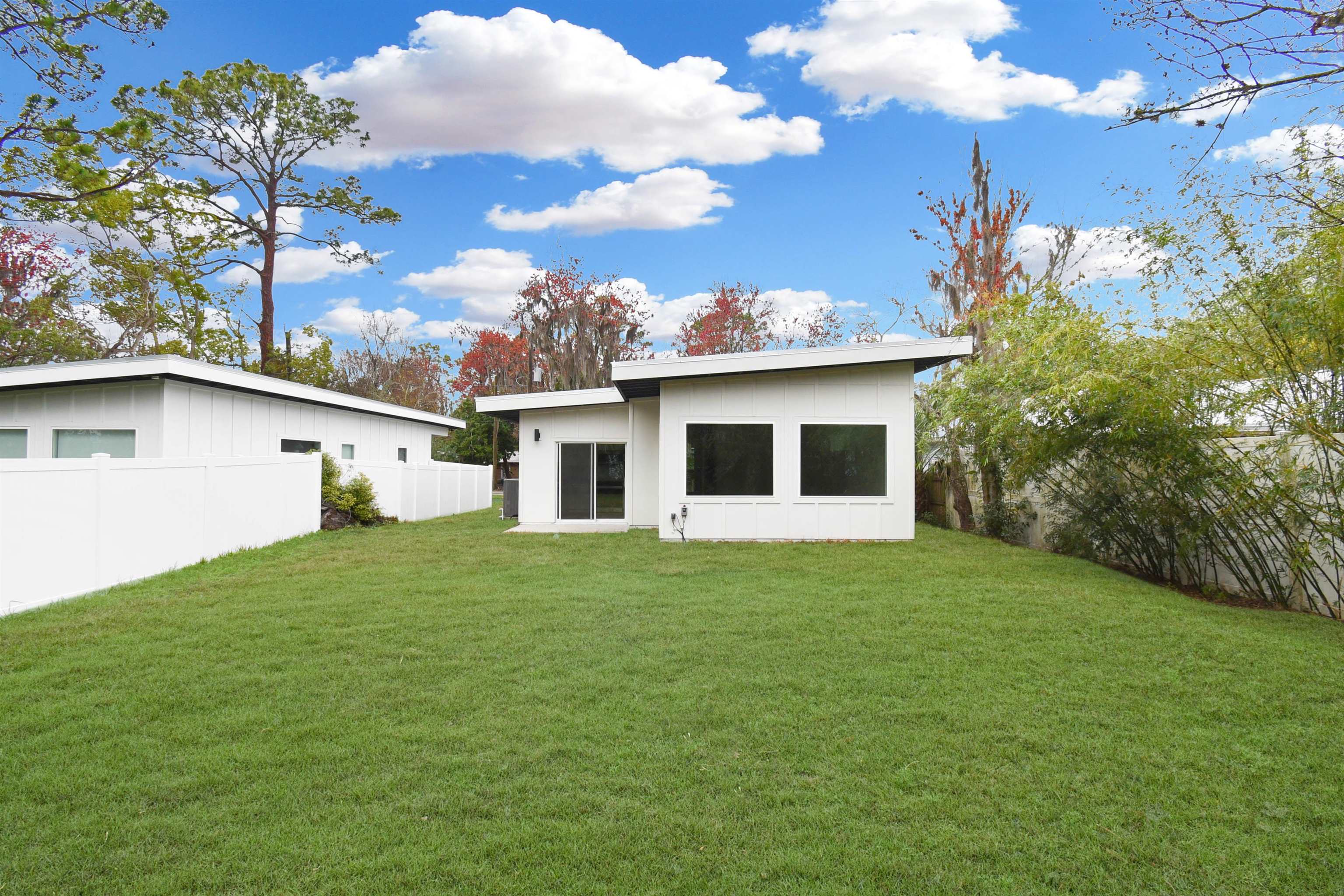 541 Columbus Street St. Augustine, FL 32084 - Photo 3 of 26 a view of a white house in front of a big yard with plants and large trees