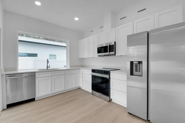 a kitchen with white cabinets and white appliances