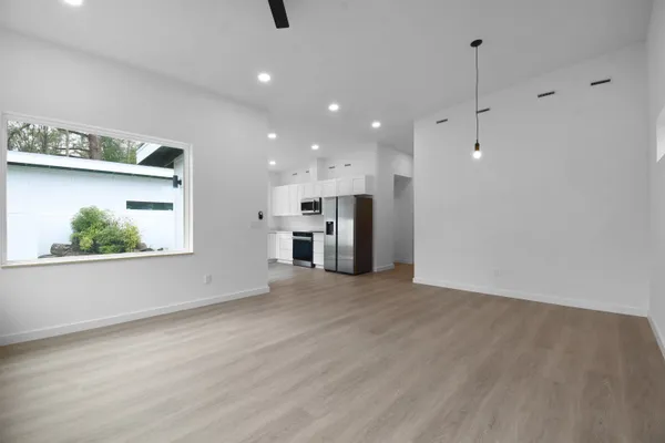 an empty room with wooden floor fan and windows