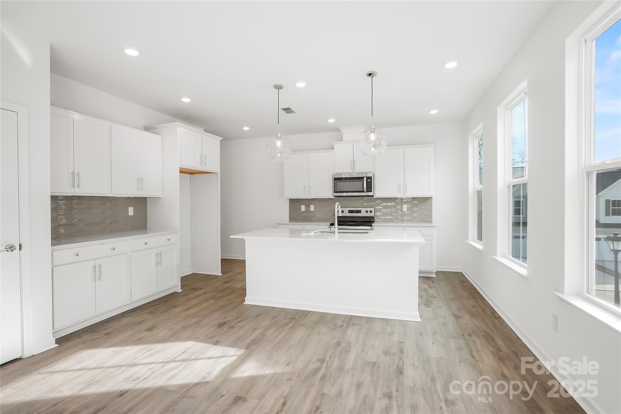 5007 Rill Court, Unit 35 Charlotte, NC 28262 - Photo 4 of 34 a kitchen with kitchen island a sink a stove a refrigerator and white cabinets with wooden floor