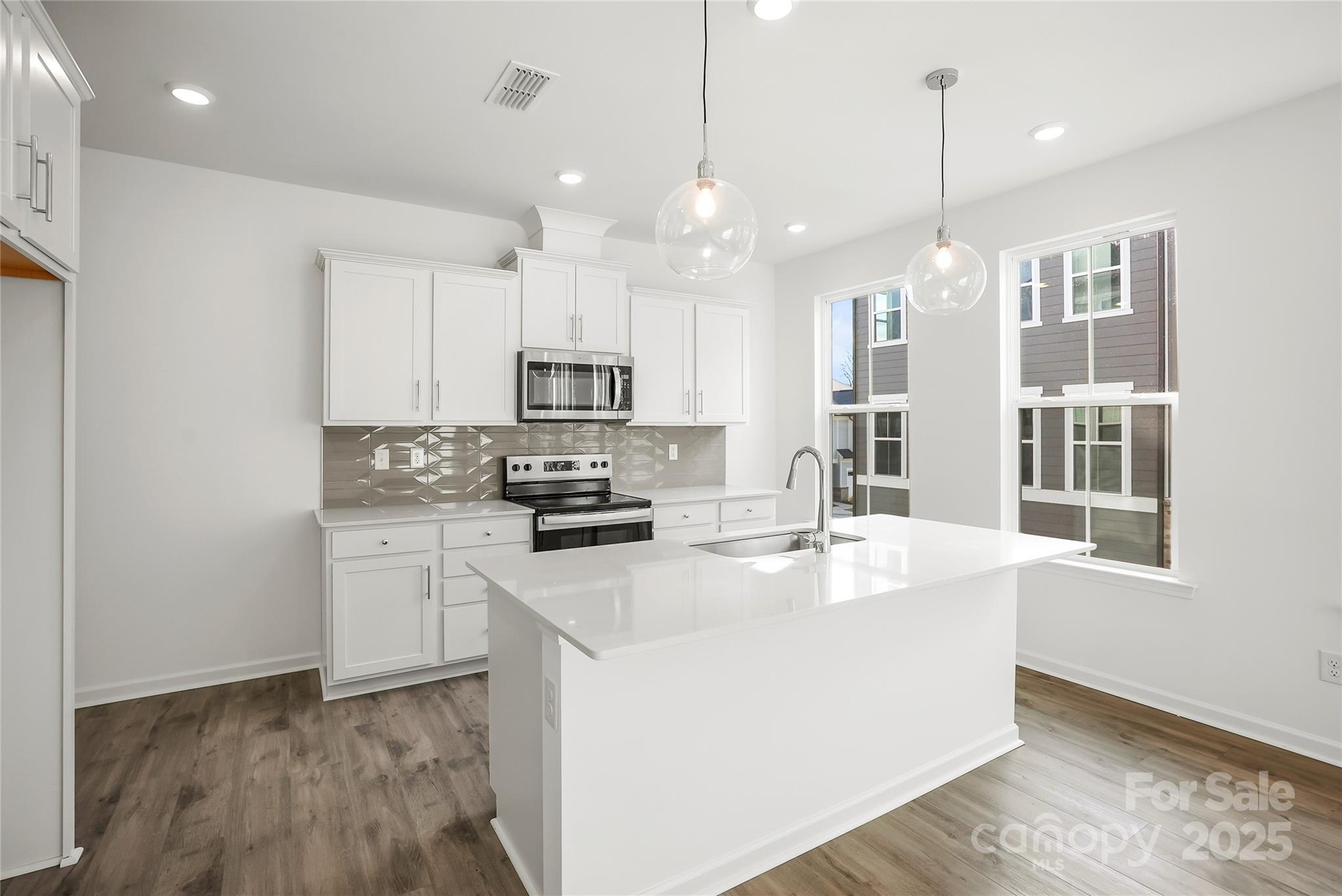 5007 Rill Court, Unit 35 Charlotte, NC 28262 - Photo 6 of 34 a kitchen with stainless steel appliances granite countertop a sink a stove a refrigerator and white cabinets with wooden floor