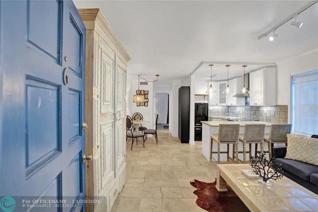 a dining hall with stainless steel appliances lots of white furniture a rug and a view of kitchen