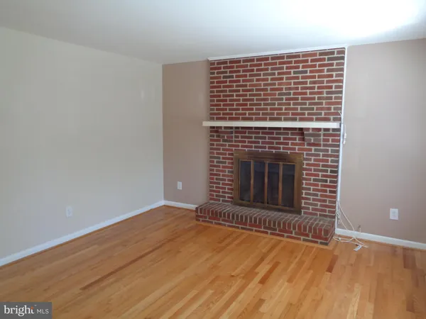a view of an empty room with wooden floor and a fireplace