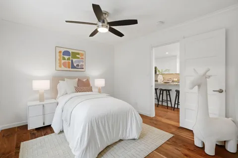 a bedroom with a bed wooden floor and a ceiling fan
