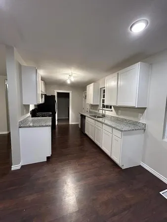a kitchen with granite countertop a refrigerator and white cabinets