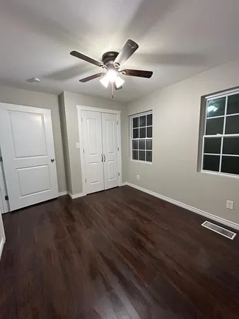 a view of empty room with wooden floor and fan