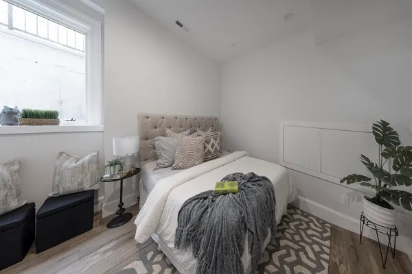 a bedroom with a bed and a potted plant on the dresser