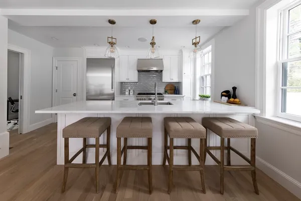 a kitchen with stainless steel appliances kitchen island granite countertop a table chairs sink and cabinets