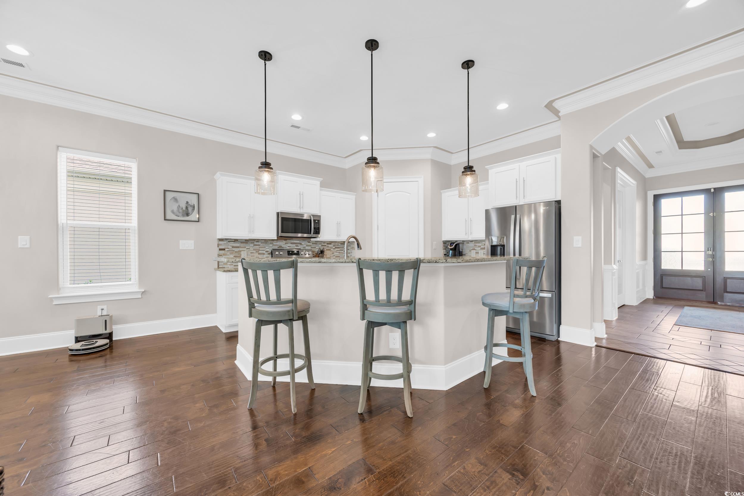 937 Bluffview Drive Myrtle Beach, SC 29579 - Photo 15 of 40 Kitchen with healthy amount of natural light, arched walkways, a kitchen bar, dark wood-type flooring, and ornamental molding