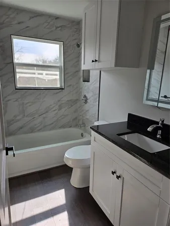a bathroom with a granite countertop toilet a sink and bathtub