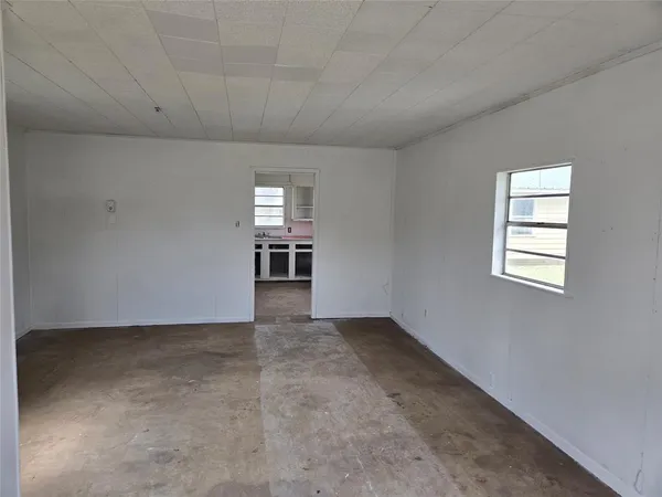 an empty room with chandelier fan and windows