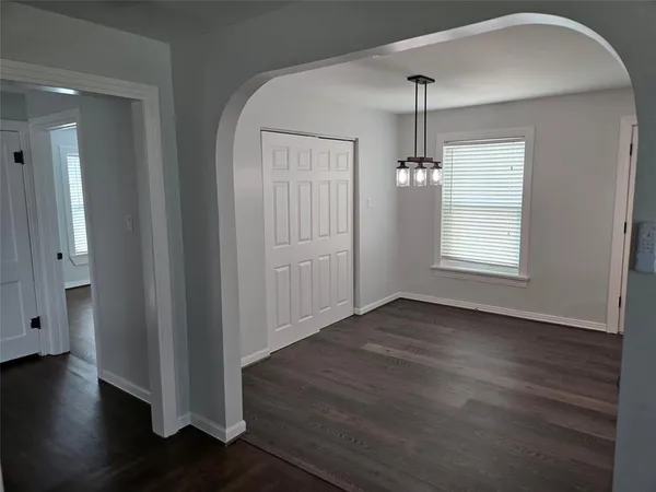 an empty room with wooden floor windows and cabinet