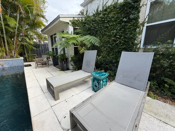 a view of a patio with table and chairs potted plants and a house