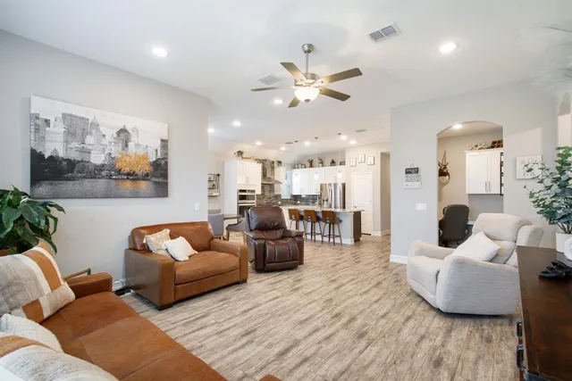 a living room with furniture kitchen view and a chandelier