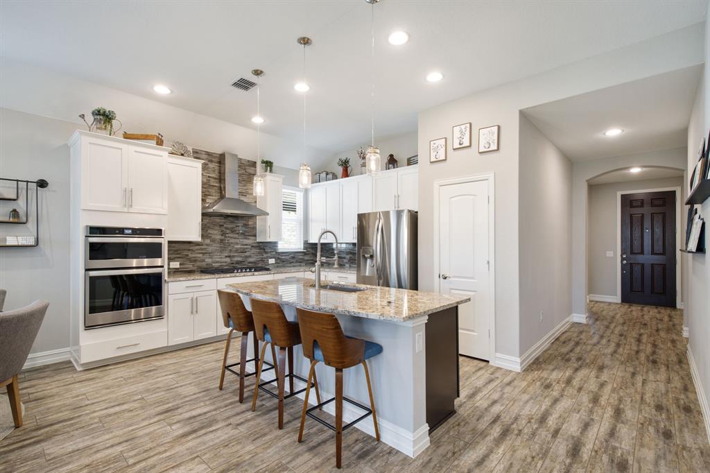 4113 Crossroads Court Oak Point, TX 75068 - Photo 8 of 33 a kitchen with stainless steel appliances a refrigerator a stove top oven and kitchen island with wooden floor