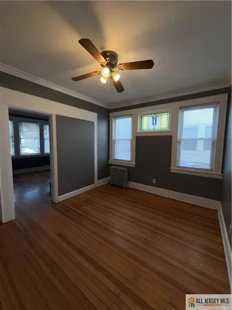 a view of an empty room with window and wooden floor