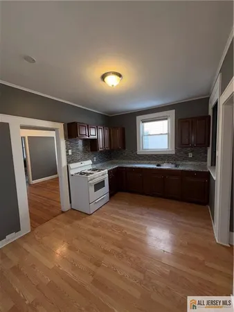 a large kitchen with stainless steel appliances granite countertop a stove a sink dishwasher a refrigerator and a oven with wooden floor