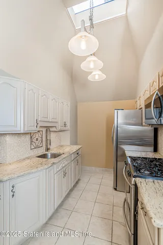 a kitchen with granite countertop stainless steel appliances a sink a stove and cabinets