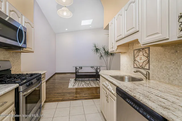 a kitchen with granite countertop a stove top oven a sink dishwasher and cabinets with wooden floor