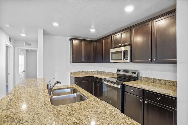 a kitchen with stainless steel appliances granite countertop a sink stove and refrigerator