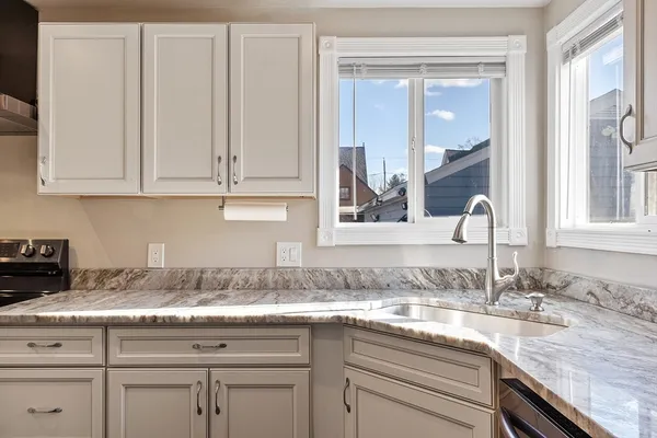 a kitchen with granite countertop stainless steel appliances white cabinets and a sink
