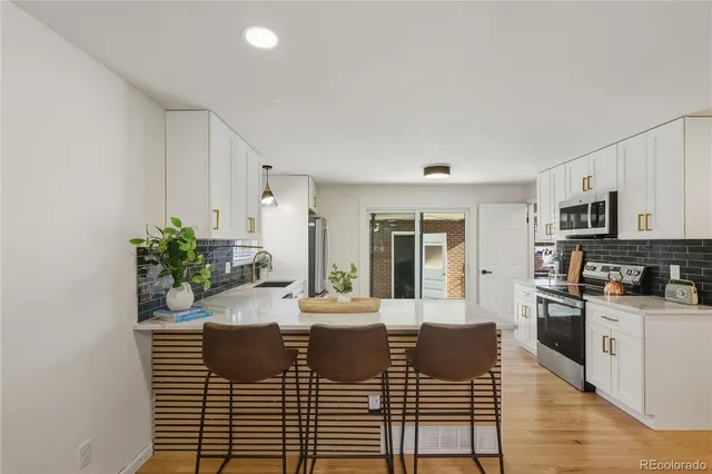 a kitchen with granite countertop a stove a sink dishwasher and white cabinets with wooden floor