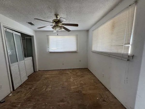 a view of a livingroom with a chandelier fan and windows