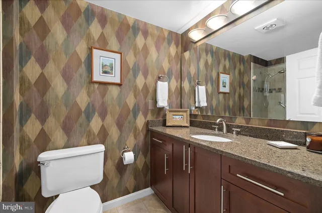 a bathroom with a granite countertop toilet sink and mirror