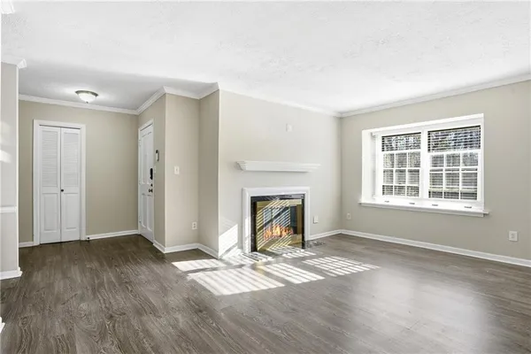 a view of an empty room with wooden floor fireplace and a window