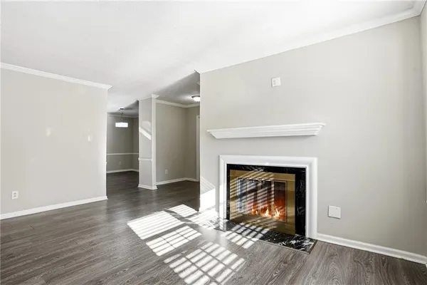 an empty room with wooden floor fireplace and windows