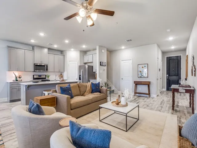 a living room with furniture kitchen view and a chandelier