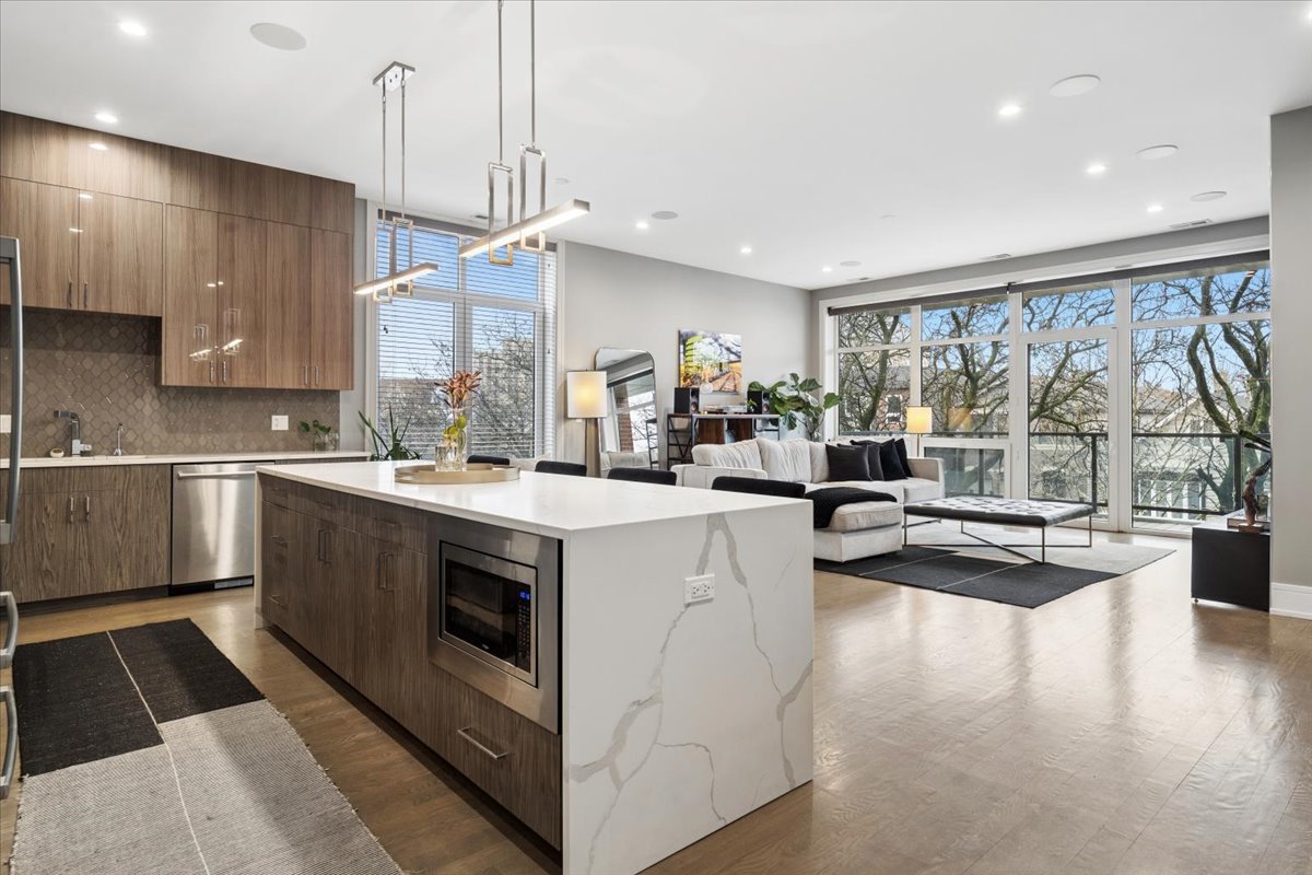 3518 West Wolfram Street, Unit 2 Chicago, IL 60618 - Photo 2 of 34 a kitchen with kitchen island a large counter top space a sink stainless steel appliances and cabinets