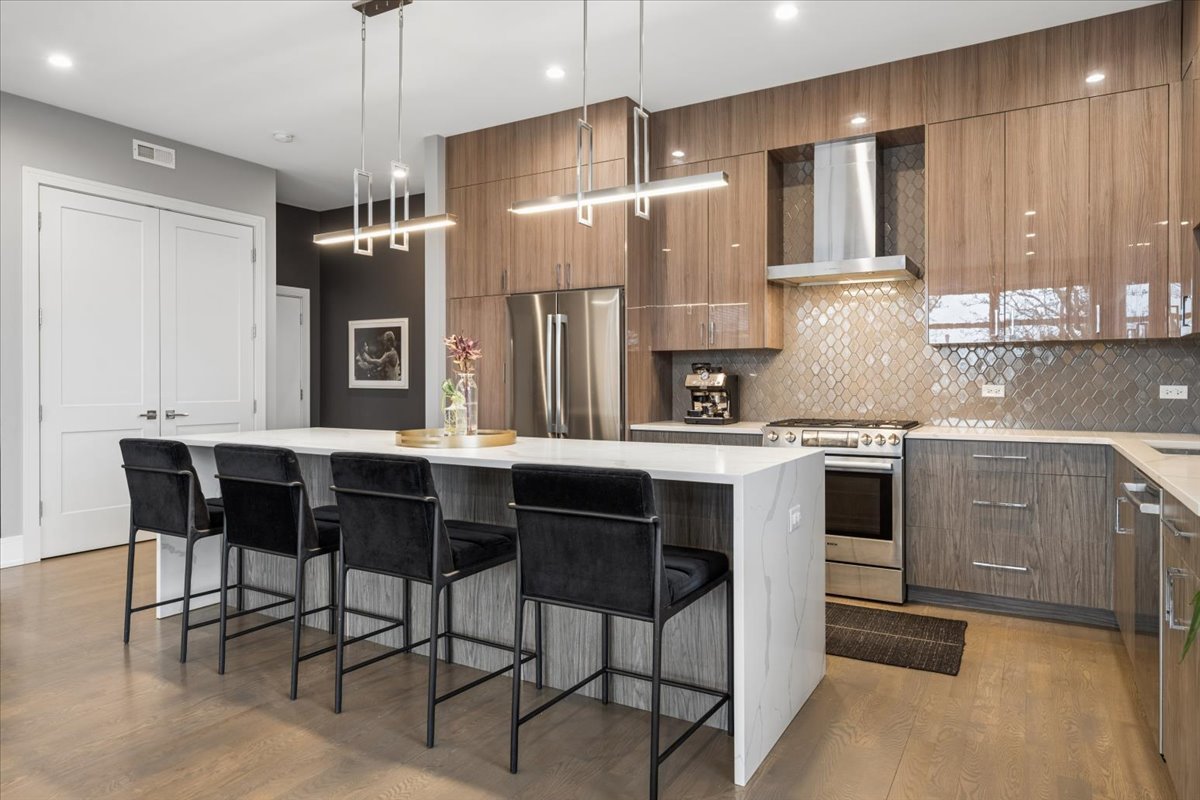 3518 West Wolfram Street, Unit 2 Chicago, IL 60618 - Photo 10 of 34 a kitchen with stainless steel appliances kitchen island granite countertop a table chairs sink and cabinets