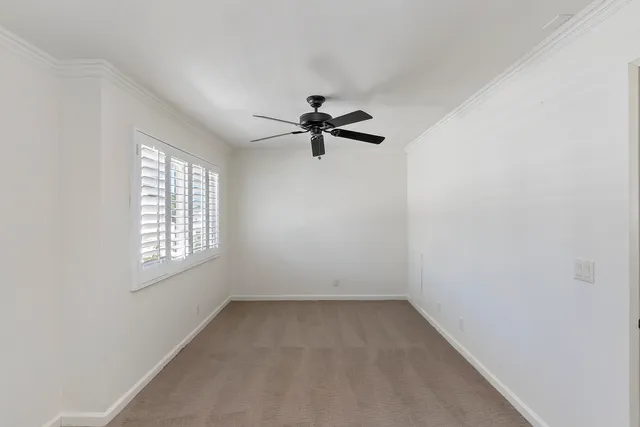 an empty room with a window and a ceiling fan