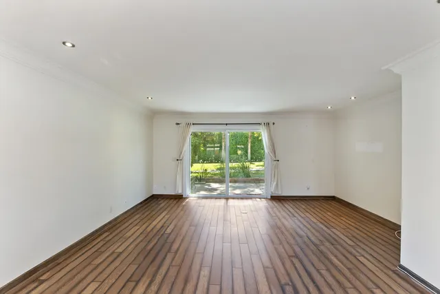 a view of an empty room with wooden floor and a window