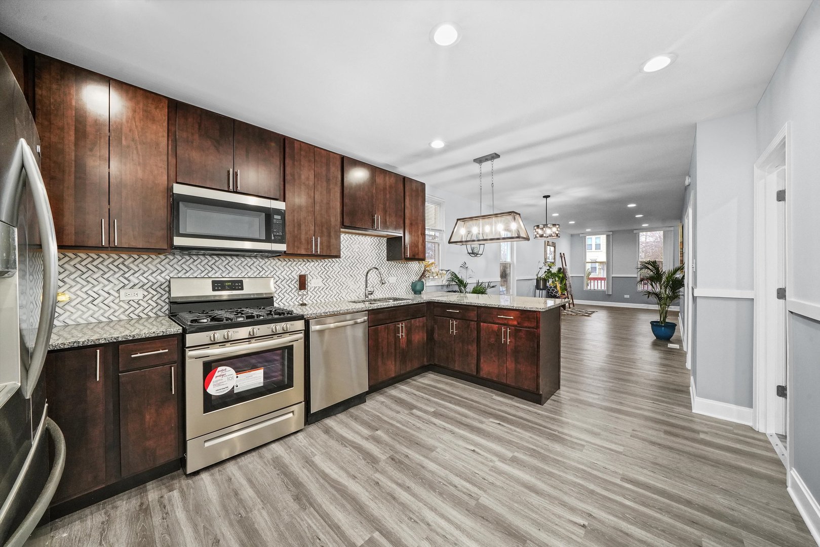 60 East 103rd Place Chicago, IL 60628 - Photo 11 of 20 a kitchen with kitchen island granite countertop wooden floors stainless steel appliances a sink and a counter space