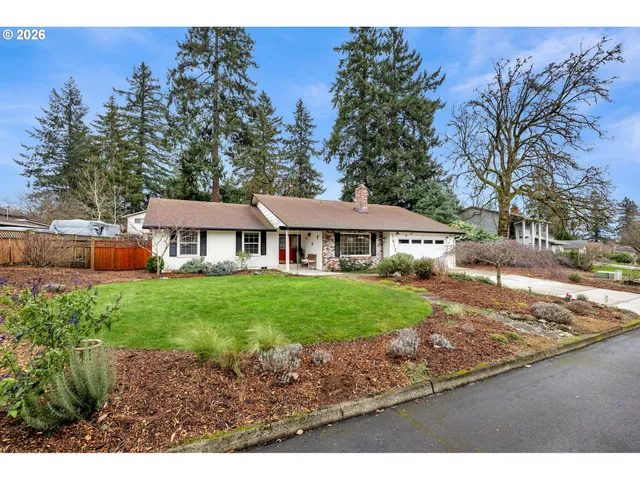 a view of a yard in front of a house with large trees