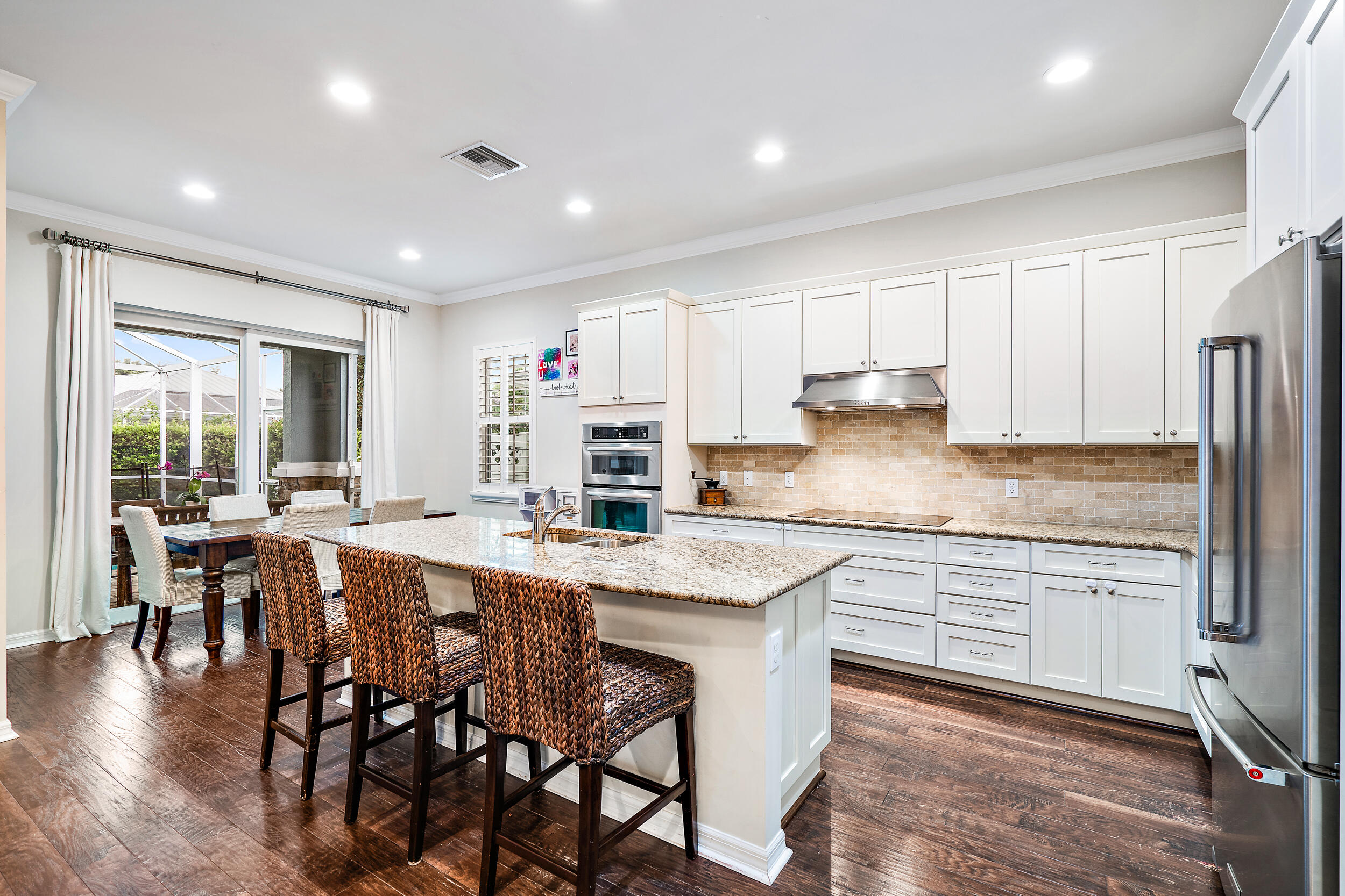 2704 Sunbury Drive Jupiter, FL 33458 - Photo 17 of 50 a kitchen with stainless steel appliances granite countertop a stove a sink a refrigerator and white cabinets with wooden floor