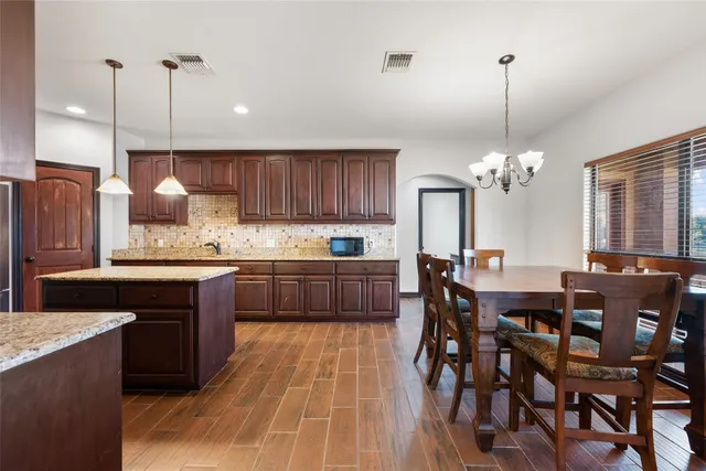 a kitchen with a dining table chairs stainless steel appliances and cabinets