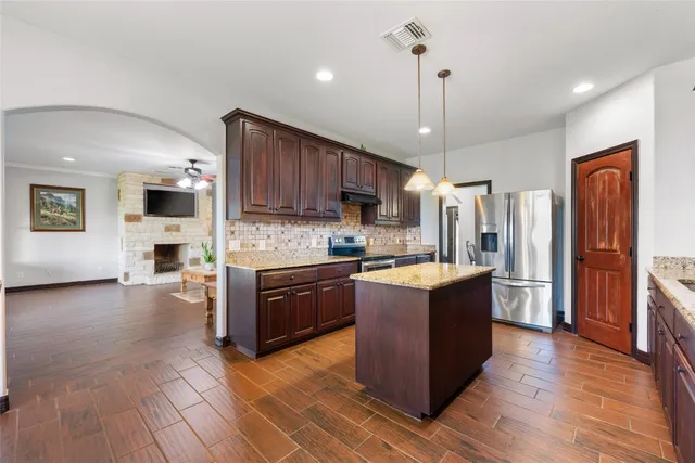 a large kitchen with stainless steel appliances granite countertop a stove refrigerator and a wooden cabinets
