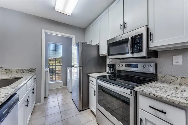a kitchen with granite countertop a stove microwave and refrigerator