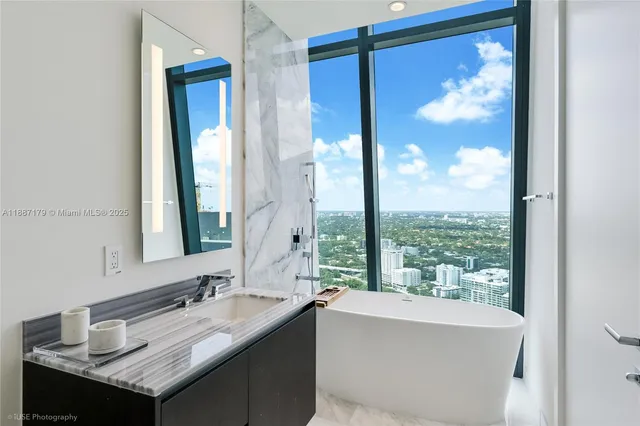 a bathroom with a granite countertop sink a bathtub and next to a window
