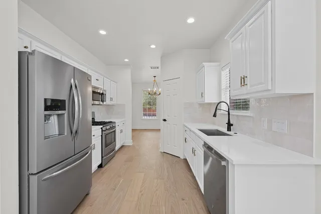 a kitchen with white cabinets sink and stainless steel appliances