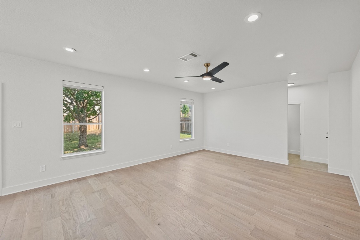 117 Waterloo Drive Kyle, TX 78640 - Photo 4 of 39 an empty room with wooden floor ceiling fan and windows