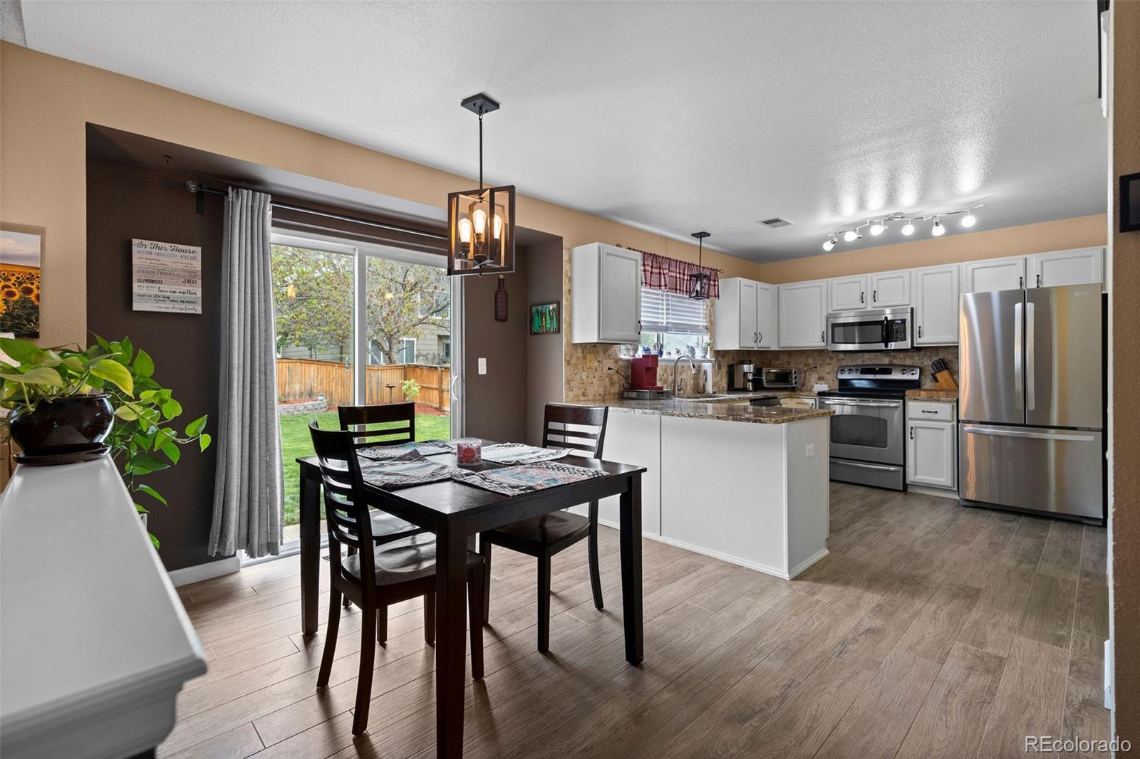 10565 Hyacinth Place Highlands Ranch, CO 80129 - Photo 9 of 33 a kitchen with stainless steel appliances granite countertop a stove a refrigerator a dining table and chairs with wooden floor