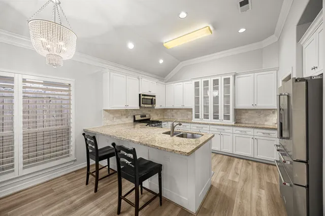 a kitchen with stainless steel appliances granite countertop a sink dishwasher a stove refrigerator and cabinets with wooden floor