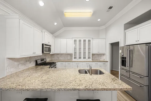 a kitchen with stainless steel appliances granite countertop a sink refrigerator and cabinets