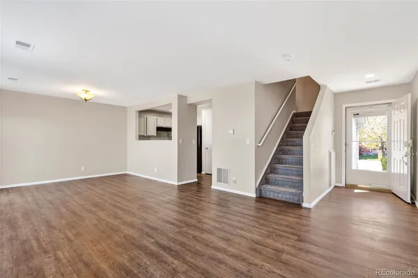a view of an empty room with wooden floor and stairs